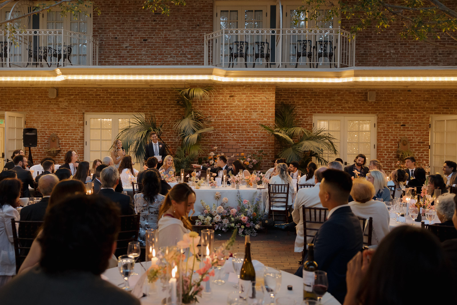 Everyone at wedding at Horton Grand Hotel toasting during speeches surrounded by colorful flowers and candles